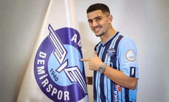 Youcef Atal en maillot d'Adana Demirspor pointant le logo du club.