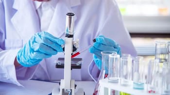 Chercheur en laboratoire utilisant un microscope avec tubes à essai.