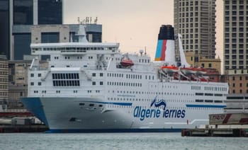 Ferry Algérie Ferries hors service en Espagne avec ville en arrière-plan.