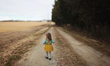 Jeune fille marchant seule sur un chemin de campagne isolé.