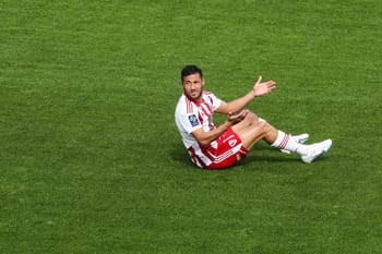 Youcef Belaili assis sur le terrain de football, en tenue sportive.