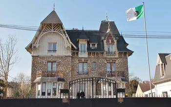 Bâtiment historique du consulat d'Algérie en France avec drapeau algérien.