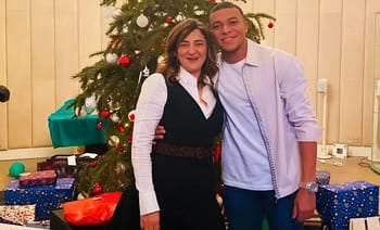 Jeune homme et femme souriants devant un sapin de Noël décoré.