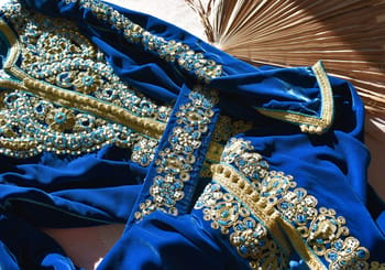 Détails d'un tissu traditionnel richement brodé en bleu et or.