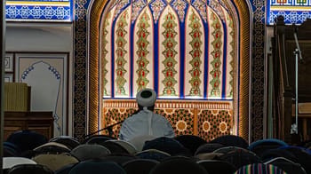 Imam prêchant dans une mosquée avec vitraux colorés.
