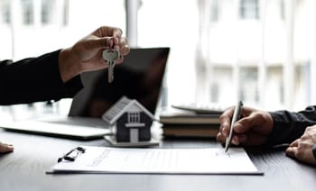 Signature d'un contrat de location avec clé et maison miniature.