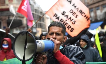 Homme avec mégaphone lors d'une manifestation pour les droits des sans-papiers.