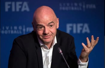 Arbitre FIFA lors d'une conférence, gesticulant en réponse à une question.