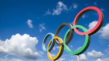 Les anneaux olympiques colorés contre un ciel bleu avec nuages.