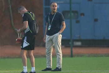 Entraîneur de football observant les joueurs lors d'un entraînement.