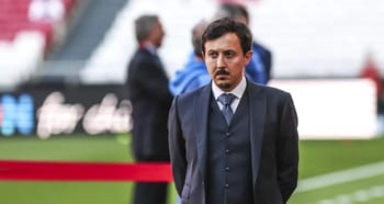 Homme en costume sur un terrain de football, ambiance de match.