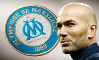 Zinedine Zidane, entraîneur de Marseille, près du logo du club.