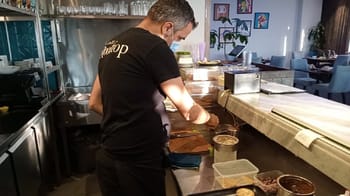 Chef Rabah Ourrad préparant un plat dans un restaurant.