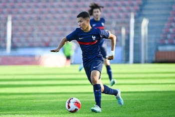Footballeur en action sur le terrain avec le ballon.