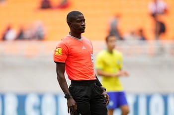 Arbitre de football en tenue orange sur le terrain lors d'un match.