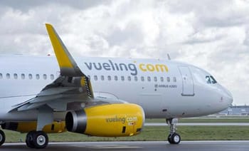Avion Vueling avec logo jaune et blanc sur piste d'aéroport.