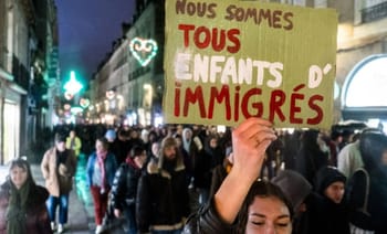 Manifestation dans la rue avec un panneau en faveur des immigrants.