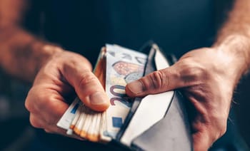 Main tenant un portefeuille avec des billets de banque en euros.