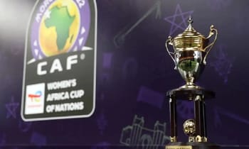 Trophée de la CAN Féminine 2024 devant un fond coloré.