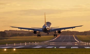 Avion en approche pour atterrir sur la piste d'aéroport au coucher du soleil.