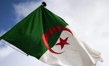 Drapeau algérien flottant dans le ciel avec nuages.
