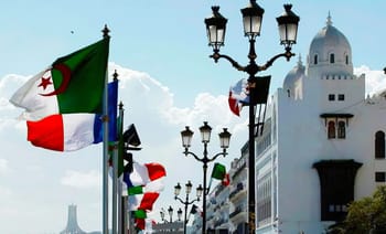 Drapeaux algérien et français flottant à Tunis avec architecture blanche.