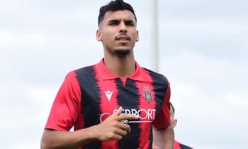 Footballer algérien en tenue d'équipe, prêt pour un match important.