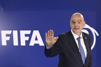 Personne en costume lors d'une conférence FIFA, faisant un geste de la main.