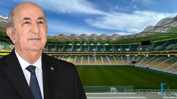 Homme en costume devant le stade Hocine Ait Ahmed à Tizi Ouzou.