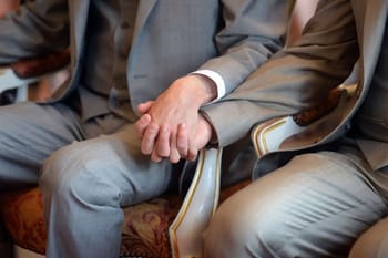 Deux hommes en costume se tenant la main lors d'une cérémonie.