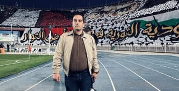 Supporter du MC Alger dans un stade avec drapeaux et tifos.