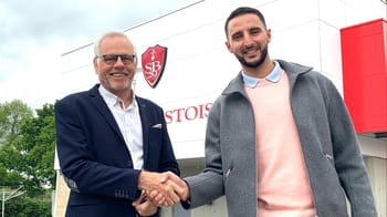 Deux hommes souriants se serrent la main devant le stade de Lille.