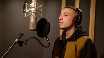 Youssef Swatt en studio, chantant dans un micro avec casque audio.