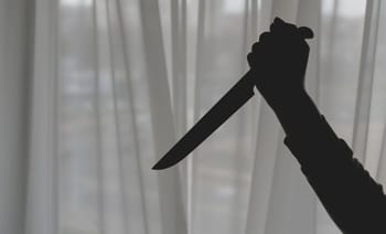 Silhouette d'un couteau tenu par une main contre une fenêtre.