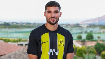 Houssem Aouar souriant en maillot de football en extérieur.