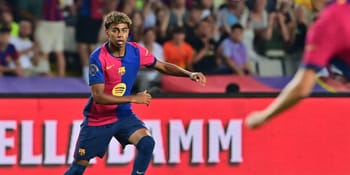 Jeune footballeur en mouvement sur le terrain avec public en arrière-plan.