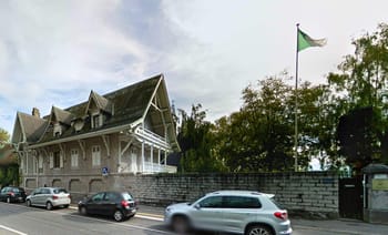 Bâtiment historique à Genève avec drapeau algérien en arrière-plan.