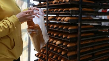Personne tenant un sac en plastique avec du pain à l'intérieur.
