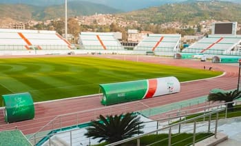 Stade Mustapha Tchaker rénové avec piste d'athlétisme et sièges modernes.