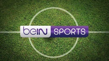 Logo beIN Sports sur terrain de football vert.