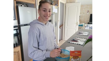 Jeune femme souriante en tenue décontractée dans une cuisine moderne.