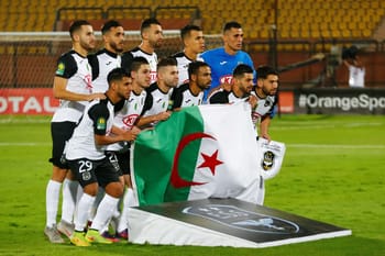 Équipe de football algérienne ES Sétif avec drapeau national en match.
