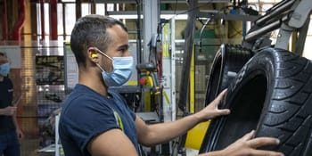 Ouvrier inspectant un pneu dans une usine de fabrication de pneus.