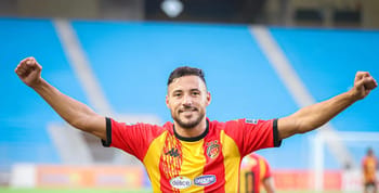 Youcef Belaili célèbre sa victoire avec un sourire et les bras levés.