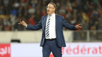 Entraîneur de football en costume lors d'un match.