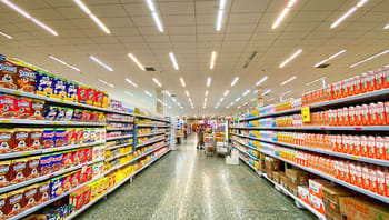 Allée de supermarché avec rayons bien fournis en produits alimentaires.