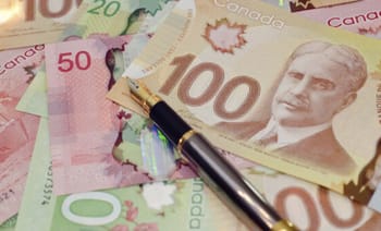 Faux billets de banque canadiens et stylo sur fond de billets authentiques.