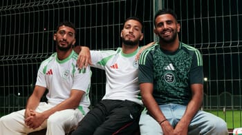 Trois joueurs algériens en maillots verts et blancs, assis sur un banc de football.