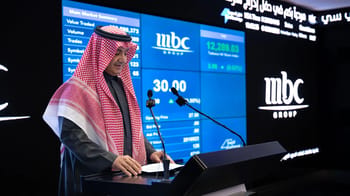 Homme en tenue traditionnelle devant un écran affichant des données financières.