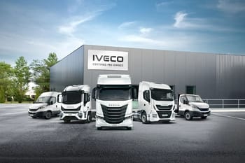 Gamme de véhicules utilitaires IVECO devant un bâtiment industriel.